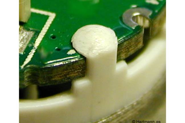 Einpressen von Kunststoffpins in eine Leiterplatte, um sie dauerhaft zu fixieren.